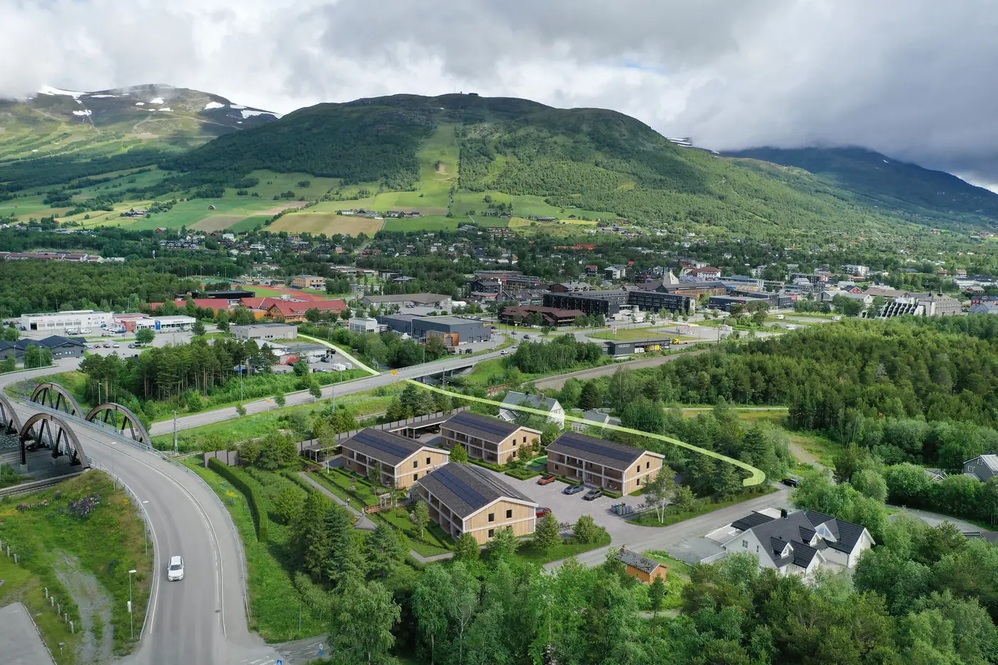 Fotomontage av bostadsprojekt med fyra huskroppar och utemiljöer, sett från luften mot fjällen